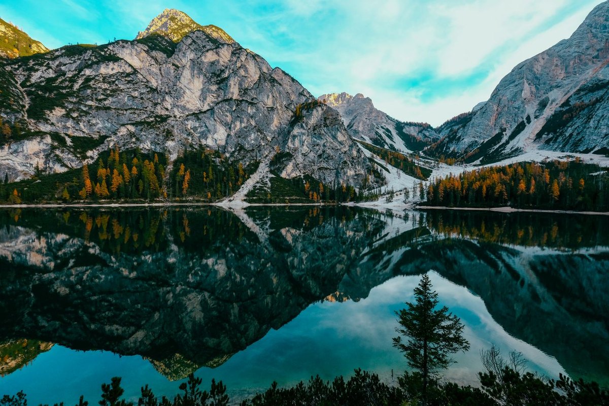 An alpine lake with a mountain and larch forest reflected in still water