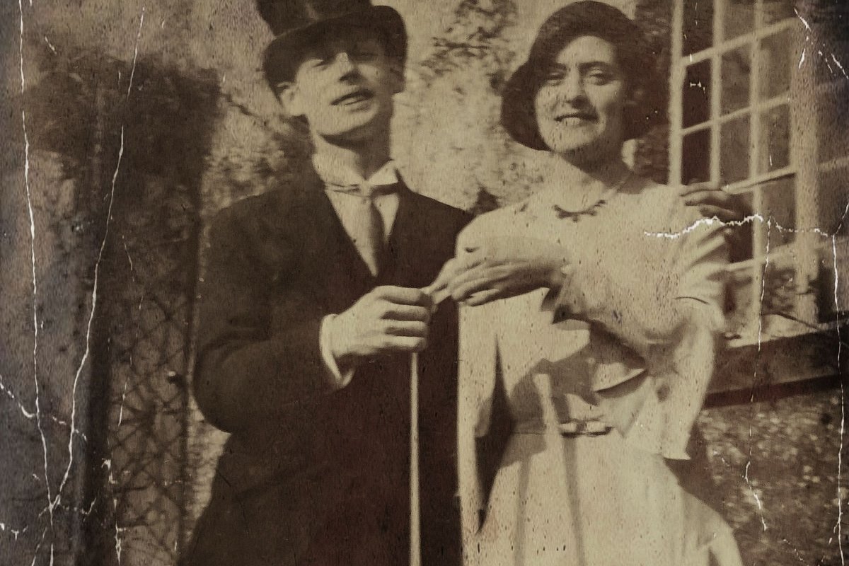 A yellowed photograph of a couple by a window, scratched and creased