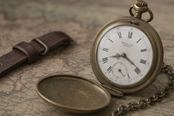 A small, soft photo of an antique pocket watch on a map, its tiny marks difficult to read